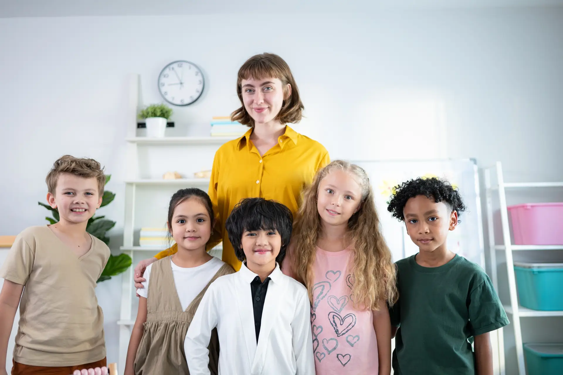 Portrait of a teacher and kids in a classroom where children have pleasure learning.